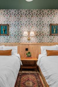 two beds in a room with a table between them at Sommer House Inn-Woodland Room in Jasper