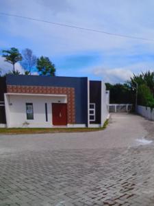 una casa con una porta rossa su una strada di mattoni di Berastagi a Berastagi