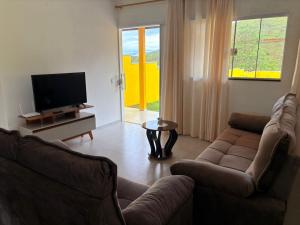 a living room with a couch and a television at Chácara Vista do Pico Agudo in Lavrinhas
