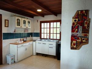 une cuisine avec des armoires blanches, un évier et une fenêtre dans l'établissement La casa del agua, à La Pedrera 7 autres photos