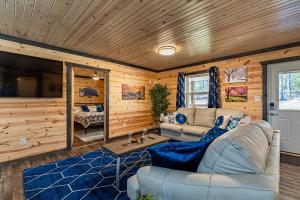 a living room with a couch and a tv at Wooded Circle - Barrel sauna, hot tub, fire pit in Hico