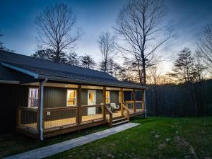 a large house with a large deck in the grass at Wooded Circle - Barrel sauna, hot tub, fire pit in Hico