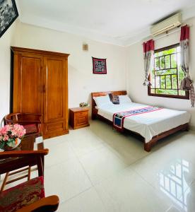 マイチャウにあるMai Ha Backpackers Hostel & Garden Loungeのベッドルーム1室(ベッド1台、木製キャビネット、テーブル付)