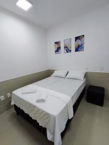 a bedroom with a large white bed with three pictures on the wall at Essenza Suites Natal in Natal