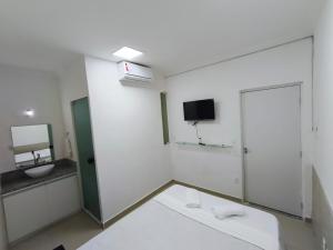a white bathroom with a sink and a toilet at Essenza Suites Natal in Natal