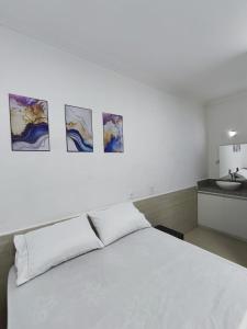 a bedroom with a white bed and a sink at Essenza Suites Natal in Natal
