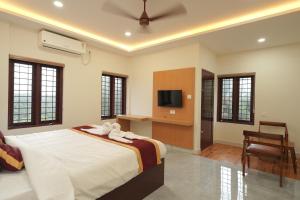 a bedroom with a bed and a tv and a chair at Winspark Inn Resort in Varkala