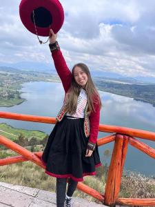 une jeune fille brandissant un chapeau en l'air dans l'établissement Cabañas lago piuray, à Chincheros