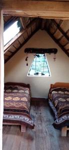 une chambre mansardée avec deux lits et une fenêtre dans l'établissement Cabañas lago piuray, à Chincheros
