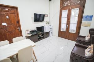 a living room with a television and a table and chairs at Villa Roemah Restoe Kolam Renang Private in Beran-kidul
