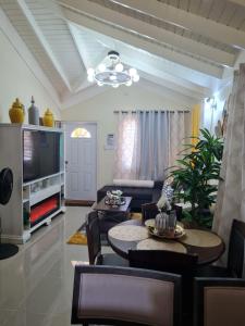 a living room with a tv and a table and chairs at Home to Comfort in Old Harbour