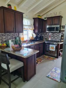 a kitchen with wooden cabinets and a large counter top at Home to Comfort in Old Harbour