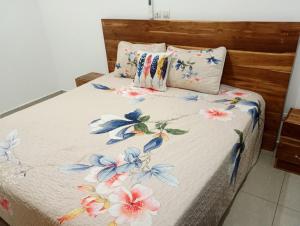 Appartement 3 pièces Tout Confort Calme - Colibri في ياموسوكرو: سرير مع لحاف عليه ورد