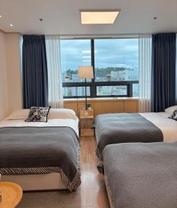 a hotel room with two beds and a large window at Hongdae sub 1min in Seoul