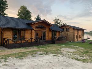 a log cabin with a porch and a house at Берег Світязя 3 in Svityazʼ