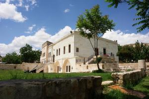a large white building with a tree in the yard at Melis Cave Hotel in Urgup