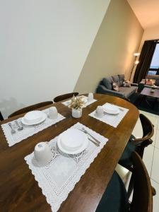 a wooden table with white plates and napkins on it at Spacious 3B3R Unit in BukitJalil in Kuala Lumpur
