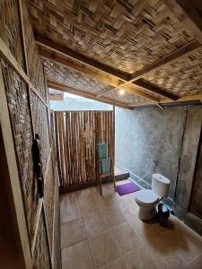 ein Badezimmer mit Toilette und Steinwand in der Unterkunft Penempuran cottage in Masbagik