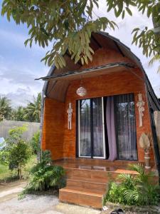 una piccola casa con una finestra rotonda e delle scale di Penempuran cottage a Masbagik