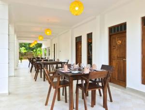 een rij houten tafels en stoelen in een kamer bij The Mammoth udawalawe in Udawalawe