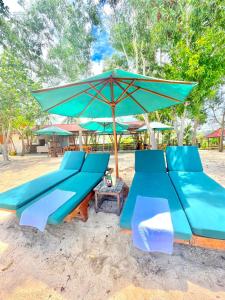 two blue benches with an umbrella on the beach at Golden Beach Hotel Lombok in Pulau Gilipoh