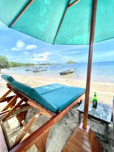 a beach with a bench and an umbrella at Golden Beach Hotel Lombok in Pulau Gilipoh +20 photos