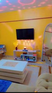 a living room with a tv on a yellow wall at Bustani Homes apartment in Kahawa