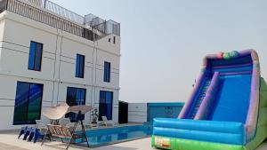 a pool with a inflatable slide next to a house at aroya in Jeddah