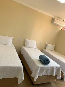 a room with two beds with white sheets and a blue pillow at Pousada Jalapão Sunset in Mateiros