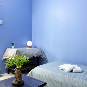ein blaues Zimmer mit zwei Betten und einem Tisch mit einer Pflanze in der Unterkunft 10min near Ipoh Town Family Old & New Style 8Px in Ipoh