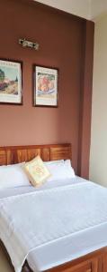 a bed in a bedroom with two pictures on the wall at Hòa An Hotel- motorbike rental in Cao Bằng