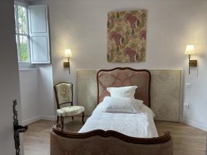 a bedroom with a bed and a chair and a window at Gîte paisible dans château avec jardin en Auvergne - FR-1-489-604 in Louchy-Montfand