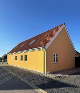 a yellow building with a brown roof on a street at Holiday Home With Courtyard In Lille Skagen in Skagen +29 photos