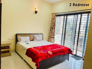 a bedroom with a bed with a red blanket on it at Candy Stay's 2BHK with Pvt Pool in Lonavala