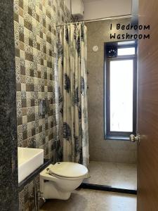 a bathroom with a toilet and a sink and a window at Candy Stay's 2BHK with Pvt Pool in Lonavala