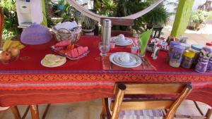 a table with a red table cloth with food on it at Pousada da Lucinha in Canoa Quebrada