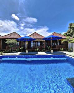 a large blue swimming pool with blue umbrellas at SEAVIEW Bungalow & Resto in Sekotong