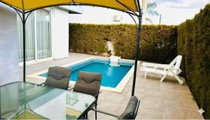 a patio with a glass table and chairs and a swimming pool at 3 bedroom villa in Oroklini