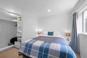 a bedroom with a bed with a plaid blanket at Wow On Wanaka Bay - beachfront living at its best in New Plymouth