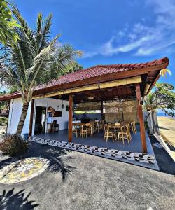 a pavilion with a table and chairs and a palm tree at SEAVIEW Bungalow & Resto in Sekotong