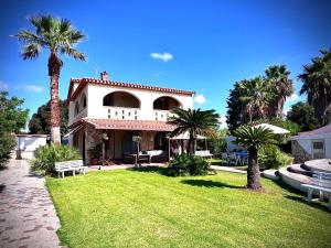 een huis met palmbomen en een grasveld bij Villa Anna in Quartu Sant'Elena