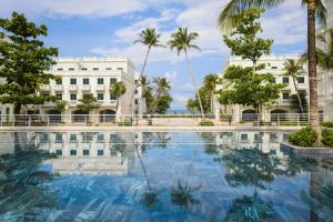 富国Herring Beach Hotel Phu Quoc的棕榈树建筑前的大型游泳池