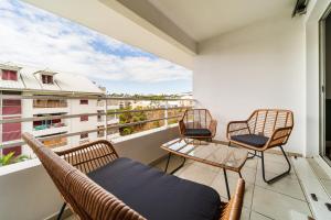 a balcony with chairs and a couch on a balcony at L Escapade - Studio tropical chic et parking prive in Saint-Denis