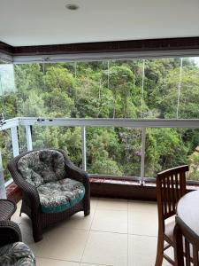 a room with a chair and a large window at Apartamento em Bertioga, ótima localização, Bertioga Residence Club in Bertioga