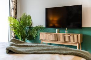 a bedroom with a flat screen tv on a green wall at L Escapade - Studio tropical chic et parking prive in Saint-Denis