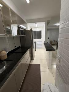 a kitchen with black counter tops and a refrigerator at Apartamento em Bertioga, ótima localização, Bertioga Residence Club in Bertioga