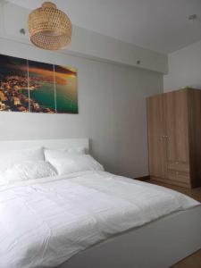 ein Schlafzimmer mit einem weißen Bett und einem Gemälde an der Wand in der Unterkunft Sunlight suite at Hope Residences in Sampong