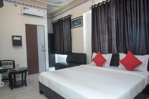 Un dormitorio con una cama con almohadas rojas y una silla en HOTEL ARAWALI UDAIPUR CITY BEST couples friendly stay, en Udaipur