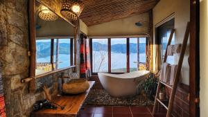 a bathroom with a tub in a room with windows at A Su Homestay Mù Cang Chải in Mù Cang Chải