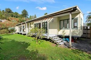 a green caravan with windows and a yard at Water's Edge Stay in Central Whangarei in Whangarei